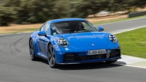 Porsche 911 Carrera 2025 azul em alta velocidade contornando uma curva em uma pista.